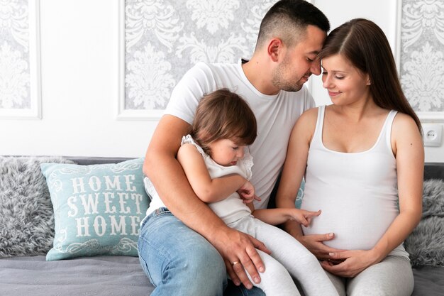 Vista frontal de la familia permanecer juntos en el sofá