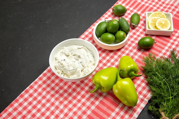 Vista frontal feijoa fresca con verduras y limón en la superficie oscura de la comida fresca de frutas