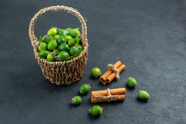 Vista frontal feijoas frescas en canasta de canela sobre superficie oscura