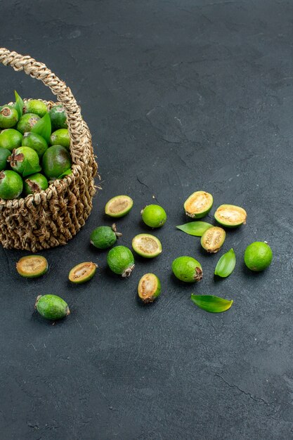 Vista frontal feijoas frescas en canasta sobre una superficie oscura con espacio de copia