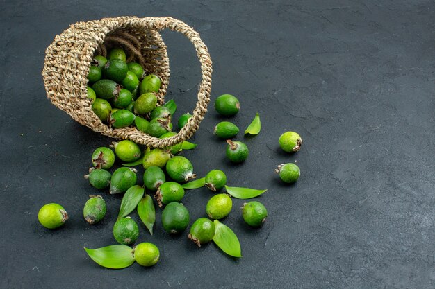 Vista frontal feijoas frescas en canasta sobre una superficie oscura con espacio de copia