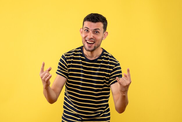 Vista frontal feliz joven en blanco y negro camiseta a rayas fondo amarillo aislado
