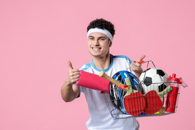 Foto gratuita vista frontal feliz joven en ropa deportiva con canasta llena de cosas deportivas