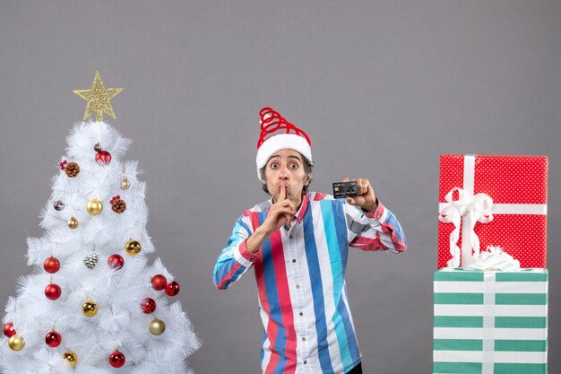 Vista frontal feliz joven señalar con el dedo que muestra el árbol de Navidad blanco