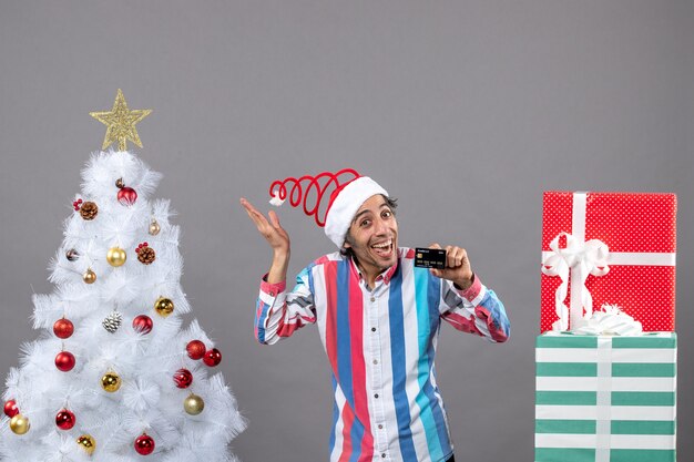 Vista frontal feliz joven con tarjeta de crédito mostrando estrella de Navidad