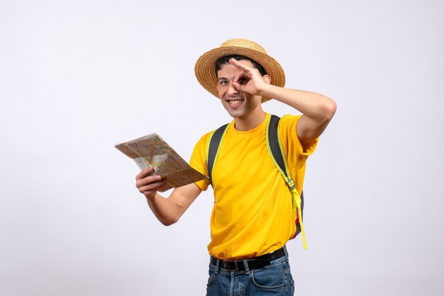 Vista frontal feliz joven turista con mochila sosteniendo mapa haciendo binoculares de mano