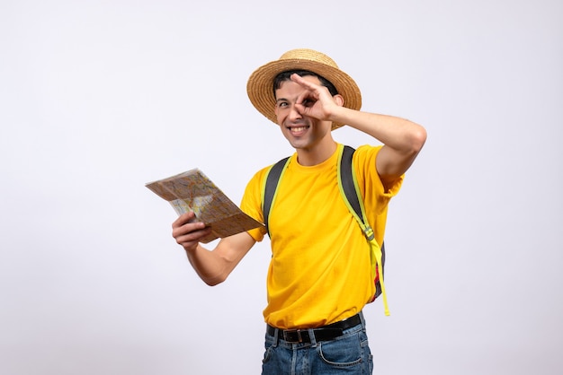 Vista frontal feliz joven turista con mochila sosteniendo mapa haciendo binoculares de mano