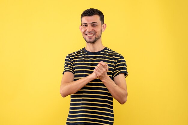 Vista frontal feliz macho joven en blanco y negro camiseta a rayas fondo amarillo aislado