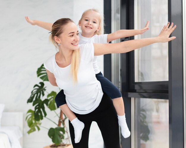 Vista frontal de la feliz madre e hija en casa haciendo ejercicio