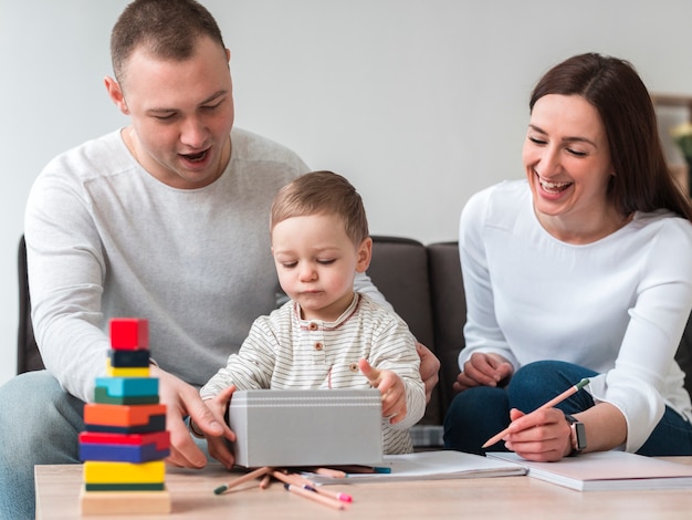 Vista frontal de la feliz madre y padre con niño en casa