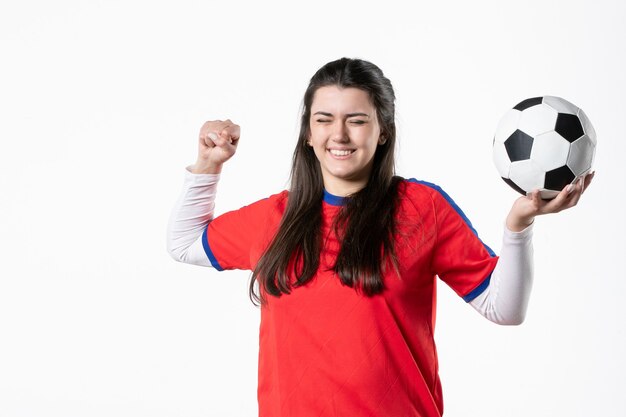 Vista frontal feliz mujer joven en ropa deportiva con balón de fútbol