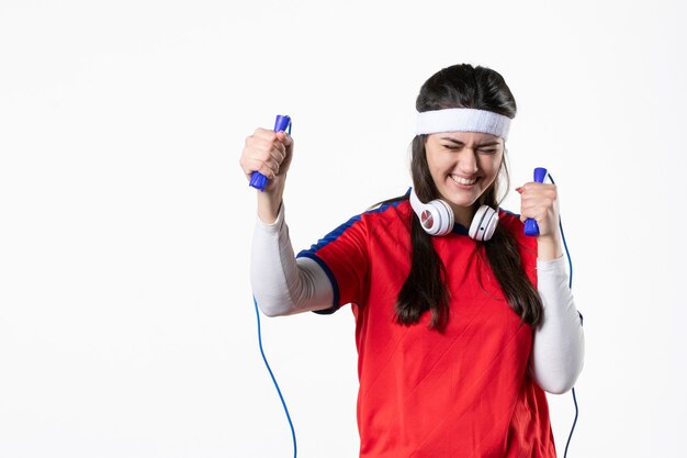 Vista frontal feliz mujer joven en ropa deportiva con cuerdas para saltar