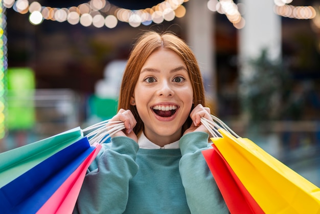 Vista frontal feliz mujer sosteniendo bolsas de colores