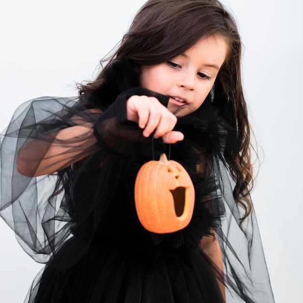 Foto gratuita vista frontal feliz niña sosteniendo una calabaza