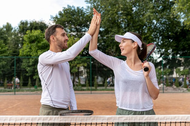 Vista frontal feliz pareja en cancha de tenis