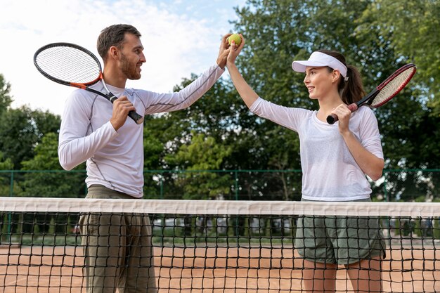 Vista frontal feliz pareja en cancha de tenis