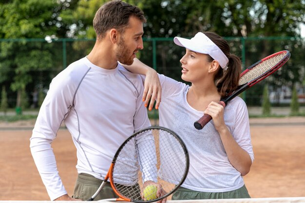 Vista frontal feliz pareja en cancha de tenis