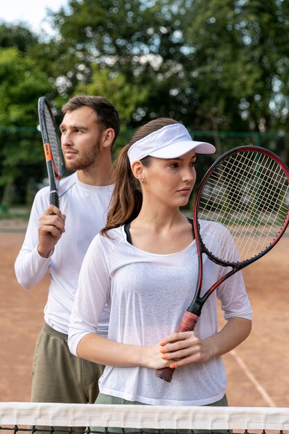 Vista frontal feliz pareja en cancha de tenis