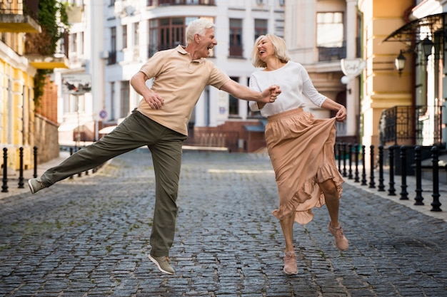 Vista frontal de la feliz pareja sonriente cogidos de la mano en la ciudad