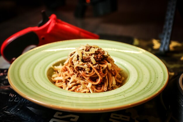 Vista frontal de fideos con carne y queso rallado en un plato