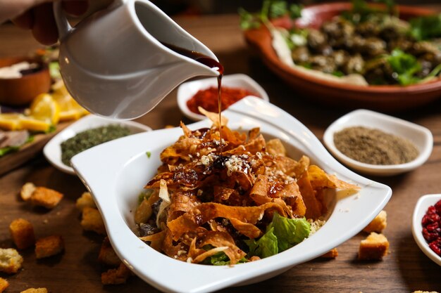 Vista frontal de fideos fritos con salsa y picatostes sobre la mesa