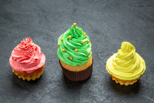 Vista frontal de la fila horizontal mini cupcakes coloridos en el espacio libre de la foto de Navidad oscura