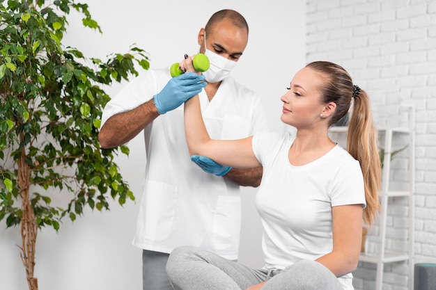 Vista frontal del fisioterapeuta masculino comprobando la fuerza de la mujer