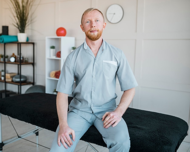 Foto gratuita vista frontal del fisioterapeuta masculino posando en la clínica