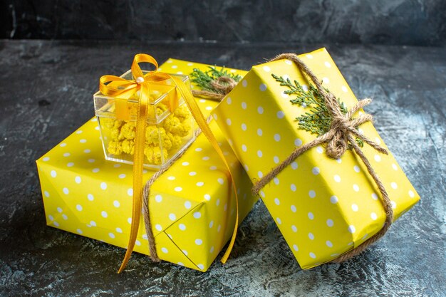 Vista frontal del fondo de Navidad con hermosas cajas de regalo amarillas sobre fondo oscuro