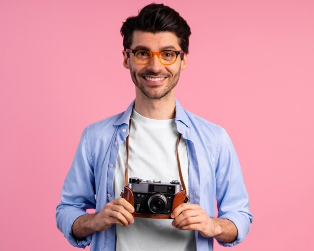 Vista frontal del fotógrafo masculino sonriente con cámara