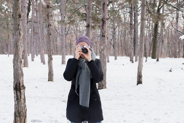 Vista frontal del fotógrafo mujer con cámara en invierno