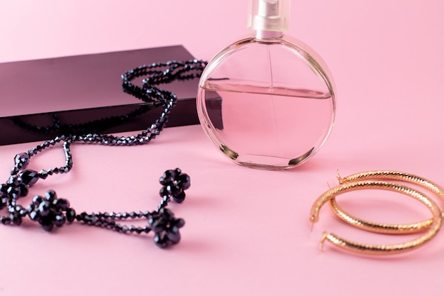 Vista frontal de fragancia elegante con collar y paquete de regalo negro en la superficie rosa
