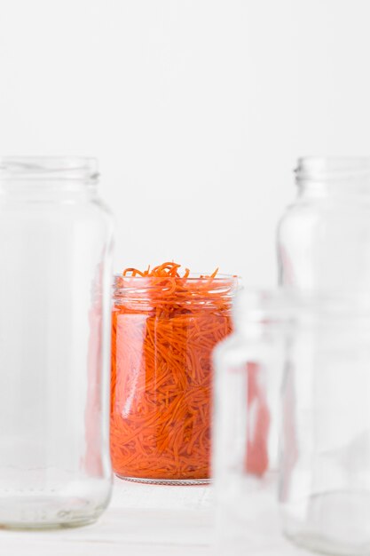 Vista frontal del frasco de vidrio con zanahorias pequeñas picadas conservadas
