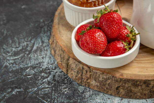 Vista frontal de fresas frescas con miel en gelatina dulce de frutas de superficie oscura