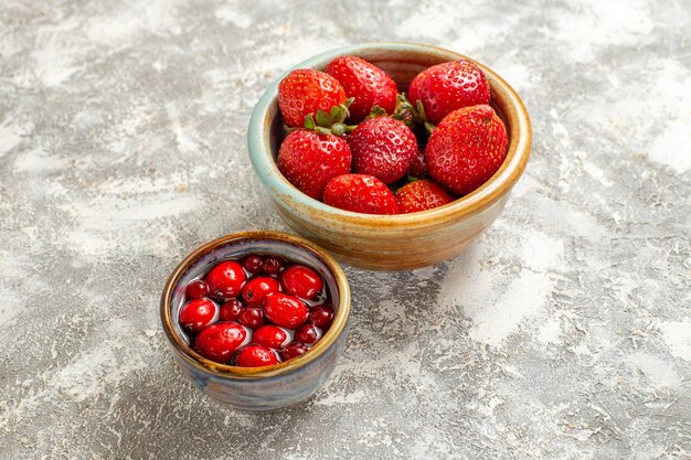 Vista frontal de fresas rojas frescas dentro de una pequeña olla sobre superficie blanca fruta baya roja