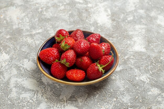 Vista frontal de fresas rojas frescas dentro de la placa en la mesa blanca frutos rojos frescos