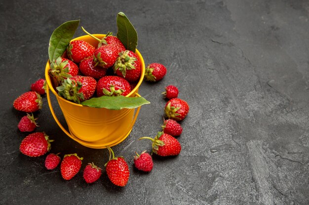 Vista frontal de fresas rojas frescas forradas sobre fondo oscuro