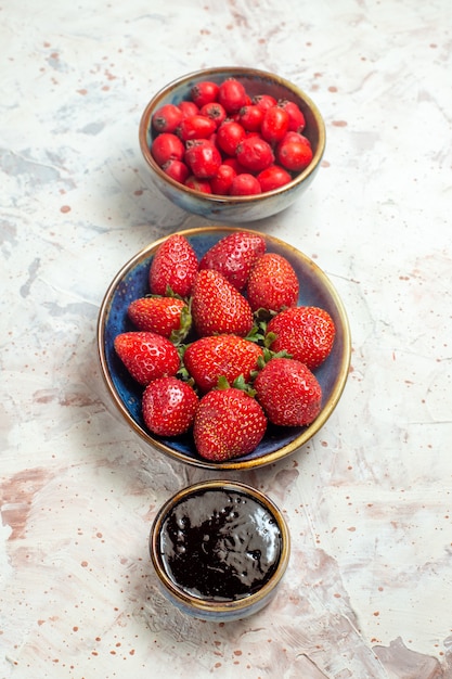 Vista frontal de fresas rojas frescas con frutos rojos sobre una mesa blanca baya roja fresca