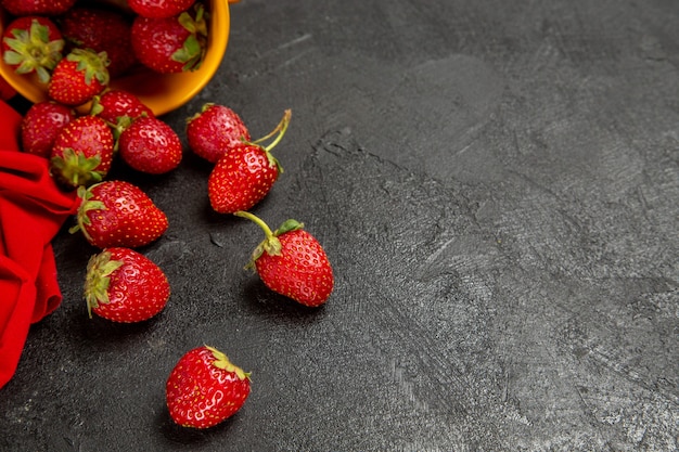 Vista frontal de fresas rojas frescas sobre el fondo oscuro