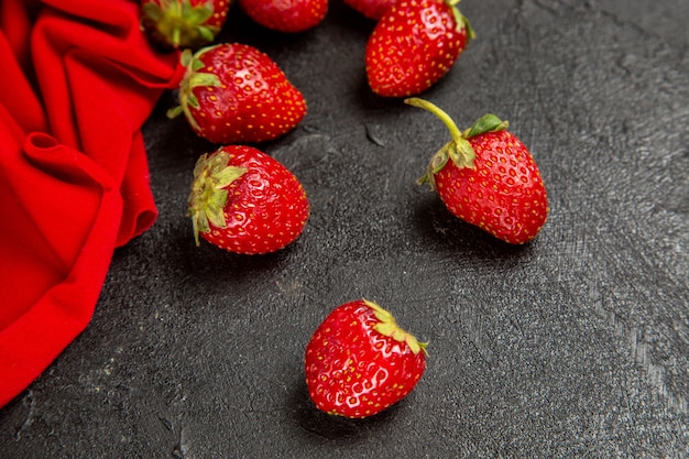 Vista frontal de fresas rojas frescas sobre el fondo oscuro