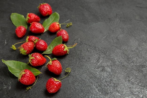 Vista frontal de fresas rojas frescas sobre el fondo oscuro