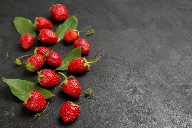 Vista frontal de fresas rojas frescas sobre el fondo oscuro