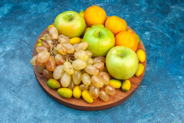 Vista frontal de frutas frescas, manzanas, mandarinas y uvas en jugo azul, fruta suave, color fotográfico, composición de vida saludable