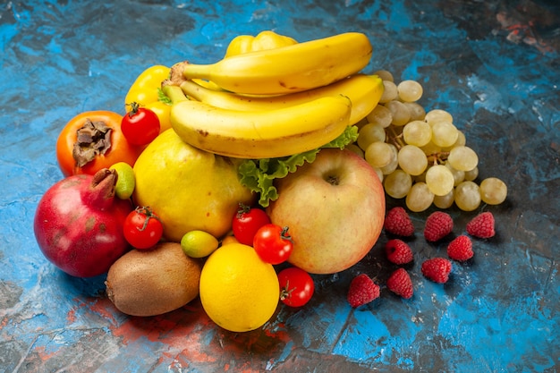 Vista frontal de frutas frescas, plátanos, uvas y otras frutas sobre fondo azul dieta suave color de salud maduro sabroso