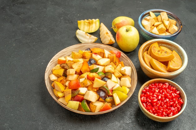 Foto gratuita vista frontal de frutas frescas en rodajas con granadas en una mesa de color gris oscuro muchas frutas salud