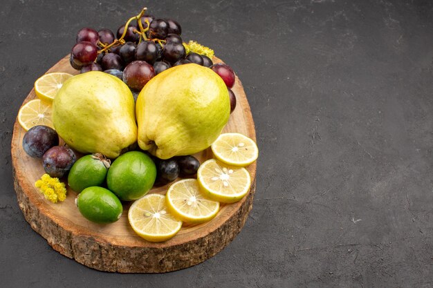 Vista frontal frutas frescas uvas rodajas de limón ciruelas y membrillos en el fondo oscuro árbol de plantas maduras de frutas frescas