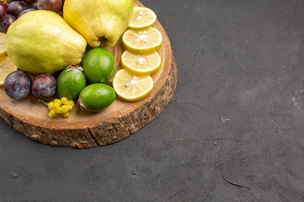 Vista frontal frutas frescas uvas rodajas de limón ciruelas y membrillos en el fondo oscuro frutas frescas planta de árbol maduro