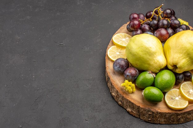 Vista frontal frutas frescas uvas rodajas de limón ciruelas y membrillos en el fondo oscuro frutas frescas planta de árbol maduro