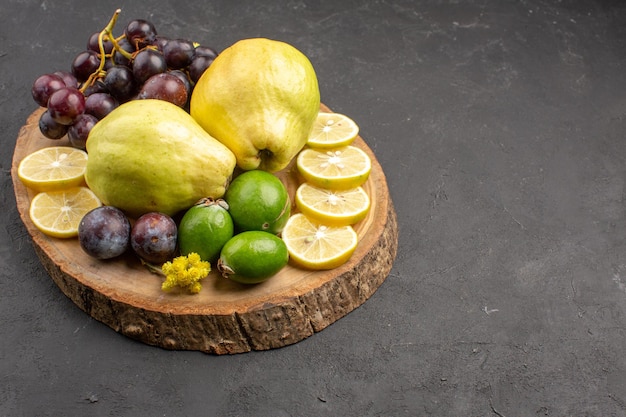 Vista frontal frutas frescas uvas rodajas de limón ciruelas y membrillos sobre fondo oscuro frutas frescas plantas de árboles maduros