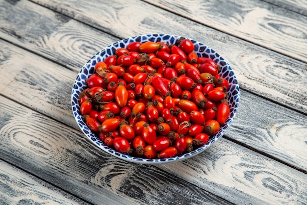 Foto gratuita vista frontal de frutos rojos frescos bayas maduras y ácidas dentro de la placa en el escritorio gris frutas berry planta de árbol de vitamina de color